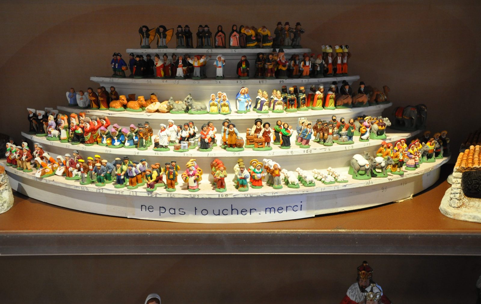 A stall of painted santons of Provence, lined up by size on tiers, at a market in Marseille